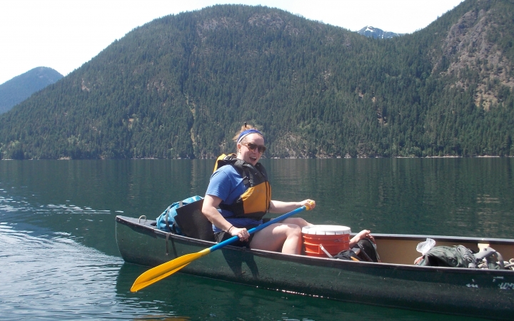 a student paddles a canoe on still water on an outward bound course in the pacific northwest
